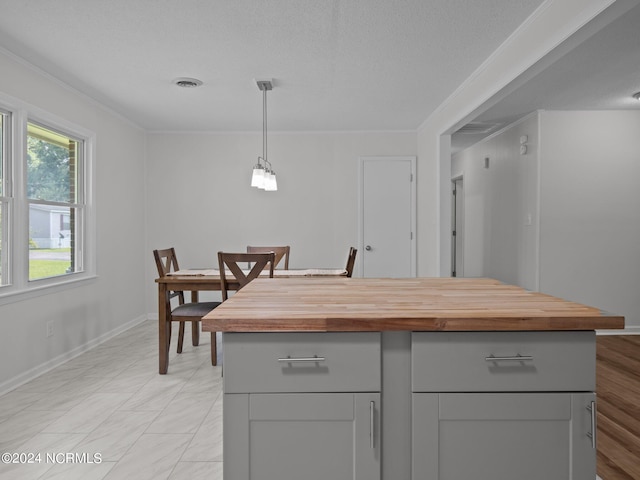 kitchen featuring gray cabinetry, pendant lighting, crown molding, and a kitchen island