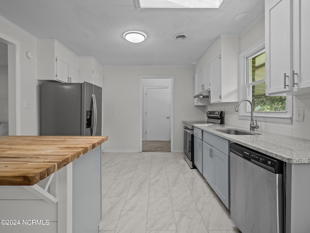 kitchen with sink, white cabinets, stainless steel appliances, backsplash, and ornamental molding