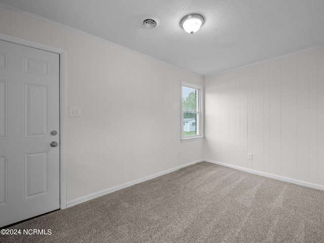 carpeted empty room featuring wooden walls