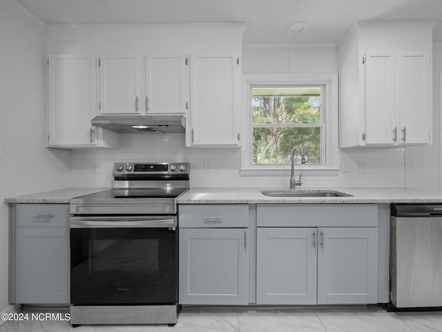 kitchen featuring sink, stainless steel appliances, light stone countertops, crown molding, and decorative backsplash