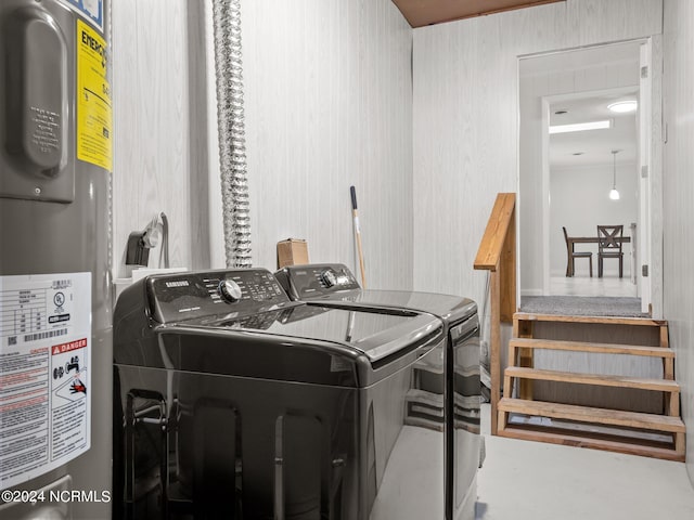 clothes washing area featuring electric water heater and washing machine and dryer