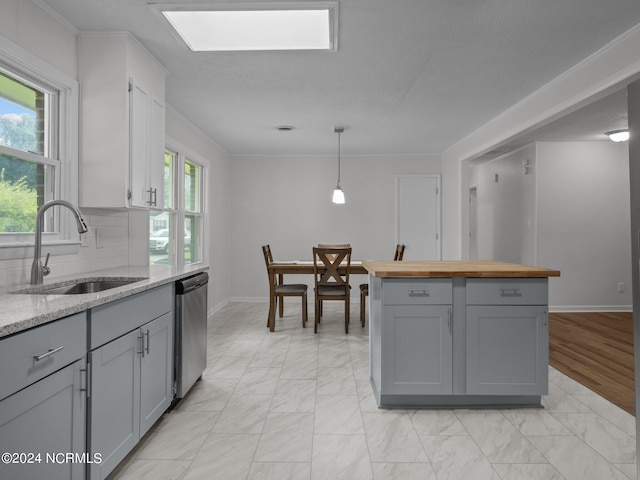 kitchen with pendant lighting, sink, stainless steel dishwasher, gray cabinets, and decorative backsplash