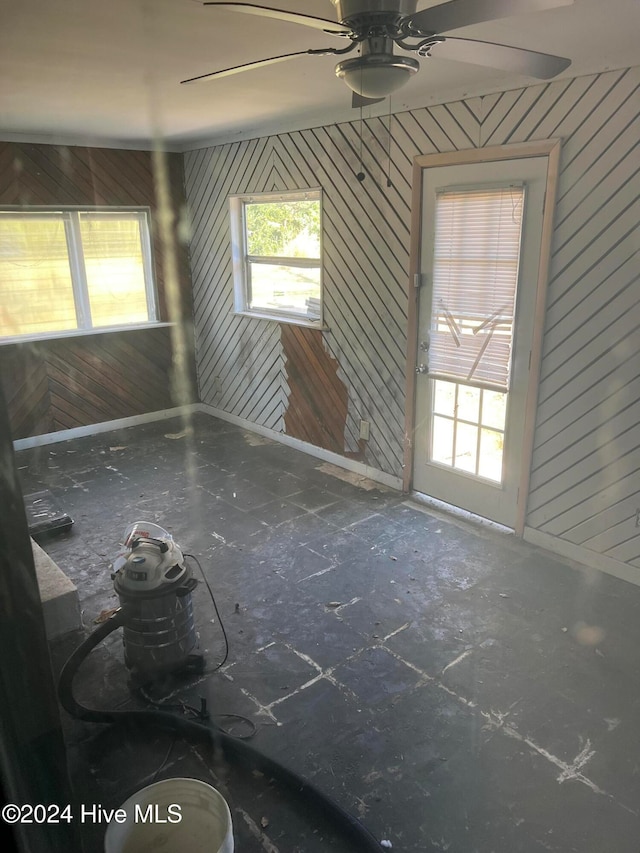 unfurnished room featuring wood walls and ceiling fan