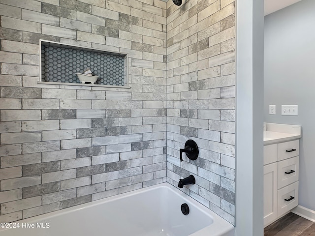 bathroom with hardwood / wood-style floors, vanity, and tiled shower / bath