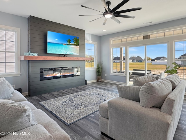 living room with a large fireplace, dark hardwood / wood-style floors, and ceiling fan