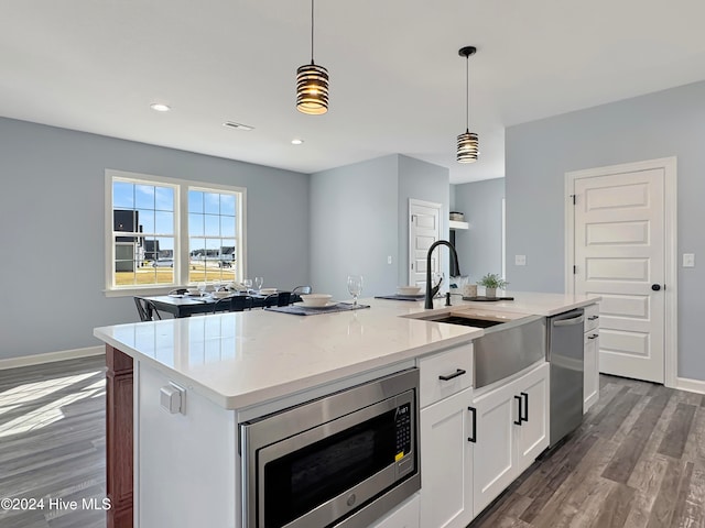 kitchen with stainless steel appliances, dark hardwood / wood-style floors, decorative light fixtures, a kitchen island with sink, and white cabinets