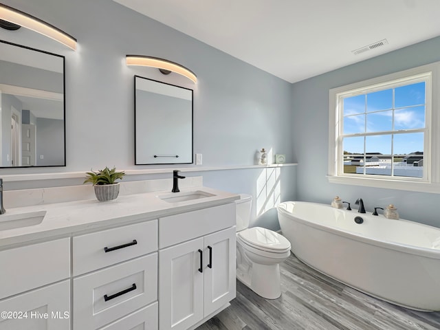 bathroom featuring hardwood / wood-style flooring, vanity, toilet, and a washtub