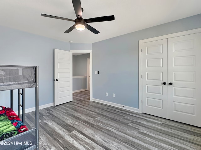 unfurnished bedroom with ceiling fan, wood-type flooring, and a closet