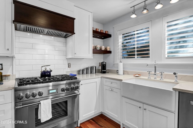 kitchen with sink, white cabinetry, stainless steel stove, hardwood / wood-style flooring, and custom range hood