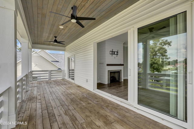 wooden deck featuring a large fireplace and ceiling fan