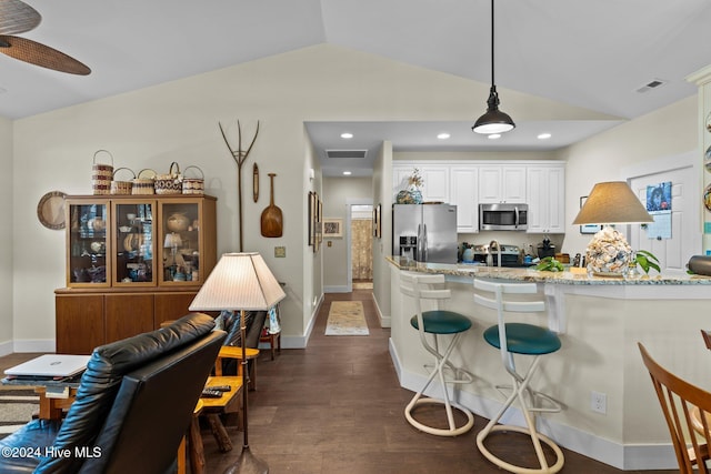 kitchen featuring light stone countertops, stainless steel appliances, pendant lighting, white cabinets, and lofted ceiling