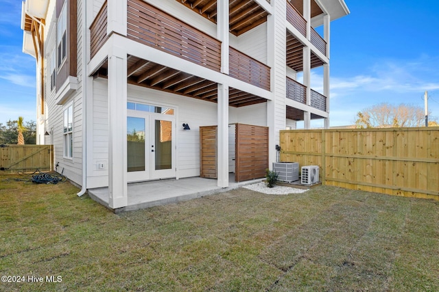 rear view of property featuring a lawn, french doors, cooling unit, and a patio