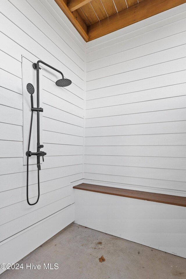 bathroom with a shower, wooden walls, and concrete flooring