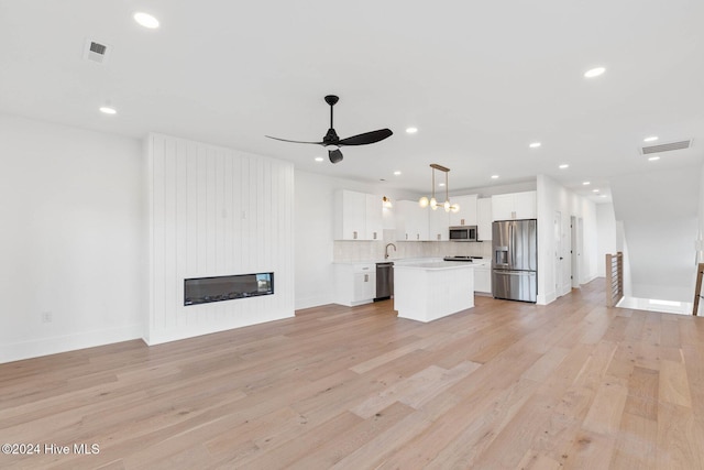 unfurnished living room with ceiling fan, a large fireplace, light hardwood / wood-style floors, and sink