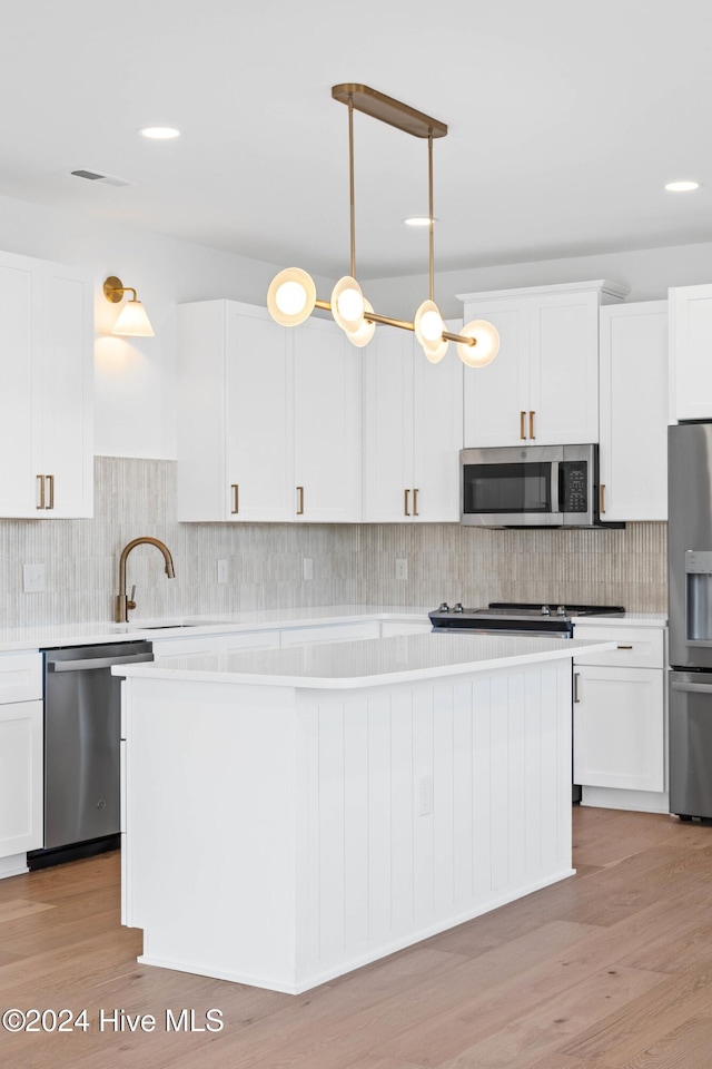 kitchen featuring sink, hanging light fixtures, light hardwood / wood-style floors, white cabinets, and appliances with stainless steel finishes