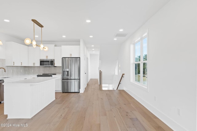 kitchen with pendant lighting, white cabinetry, stainless steel appliances, and tasteful backsplash