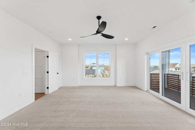 carpeted empty room with ceiling fan and a wealth of natural light