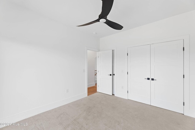 unfurnished bedroom featuring a closet, ceiling fan, and light colored carpet