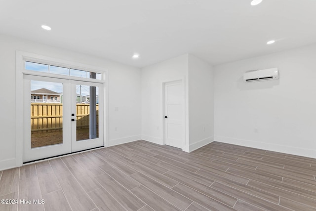 spare room featuring french doors and a wall mounted air conditioner