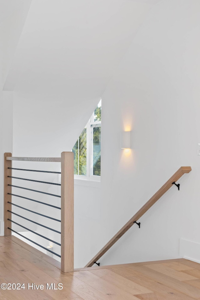 staircase featuring hardwood / wood-style flooring and lofted ceiling