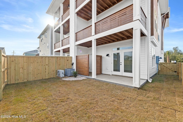 rear view of property featuring french doors, central AC unit, and a lawn