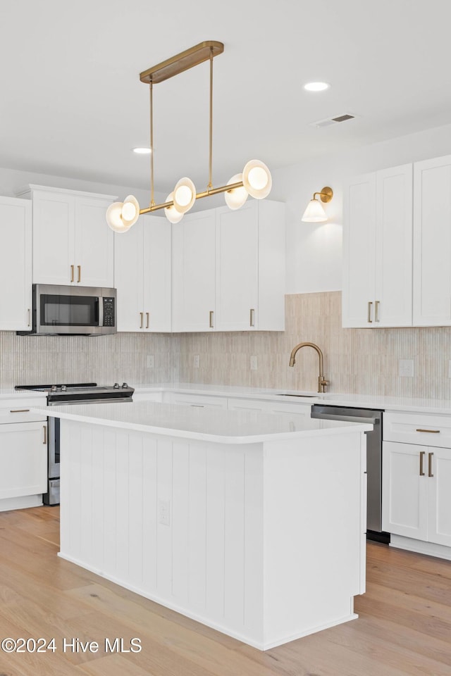 kitchen with pendant lighting, sink, white cabinets, and stainless steel appliances