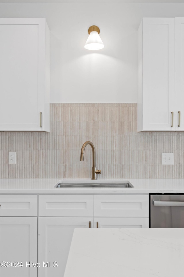 kitchen featuring backsplash, dishwasher, white cabinetry, and sink