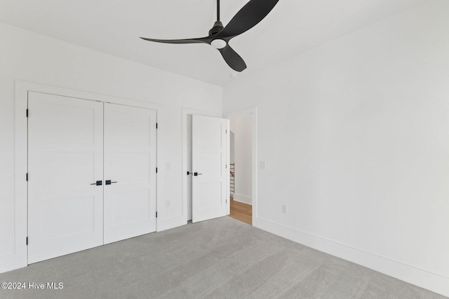 unfurnished bedroom featuring ceiling fan, light colored carpet, and a closet