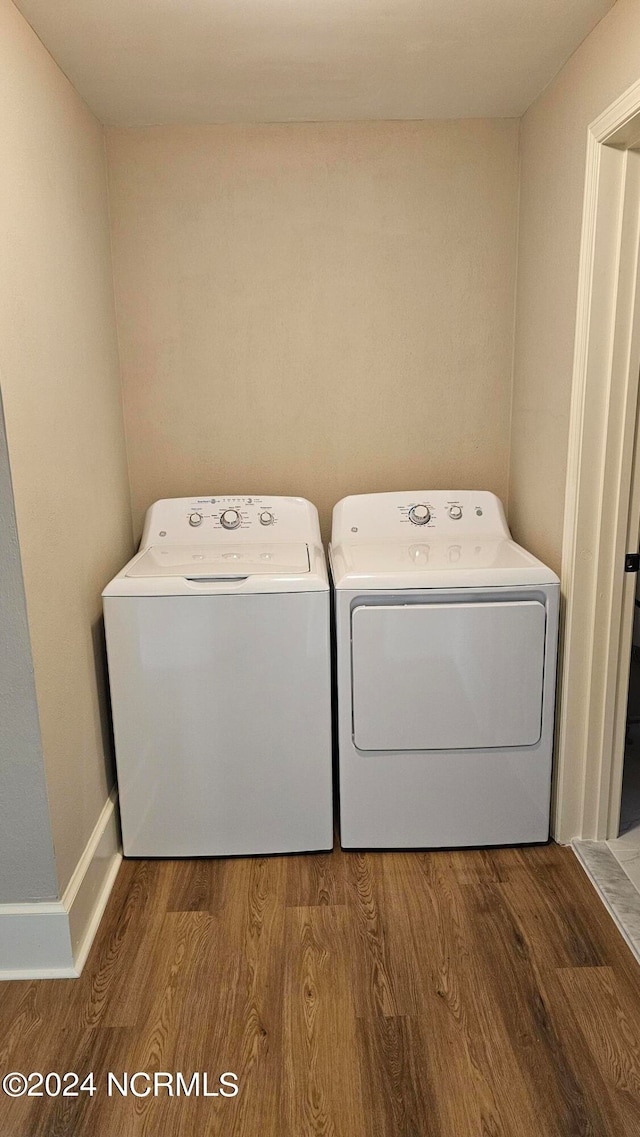 clothes washing area with hardwood / wood-style floors and washer and dryer