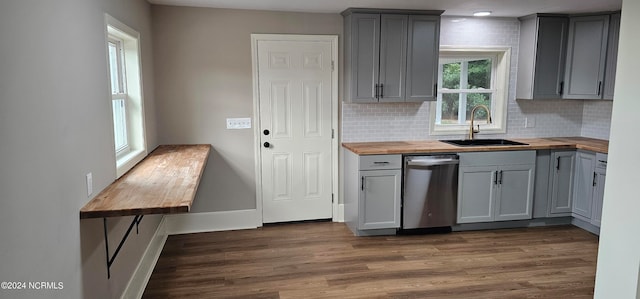 kitchen with dark wood-type flooring, gray cabinets, wooden counters, stainless steel dishwasher, and sink