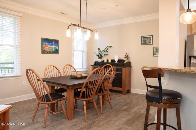 dining room featuring dark hardwood / wood-style floors, ornamental molding, and a healthy amount of sunlight