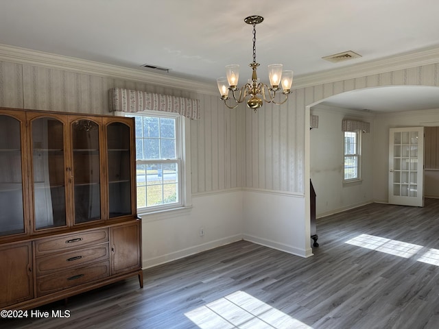 unfurnished dining area featuring crown molding, wood-type flooring, and an inviting chandelier