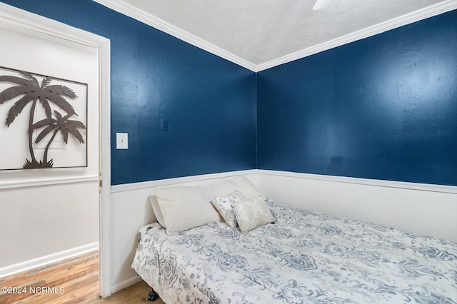 bedroom with wood-type flooring, a textured ceiling, ornamental molding, and ceiling fan