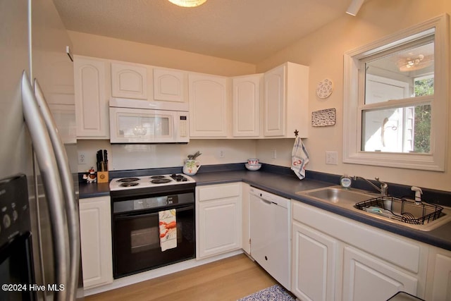 kitchen featuring white cabinetry, white appliances, sink, and light wood-type flooring