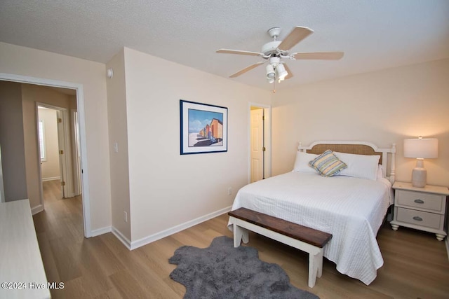 bedroom with ceiling fan, a textured ceiling, and light wood-type flooring