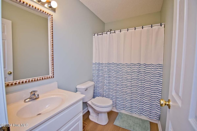 bathroom with a shower with shower curtain, a textured ceiling, hardwood / wood-style floors, vanity, and toilet