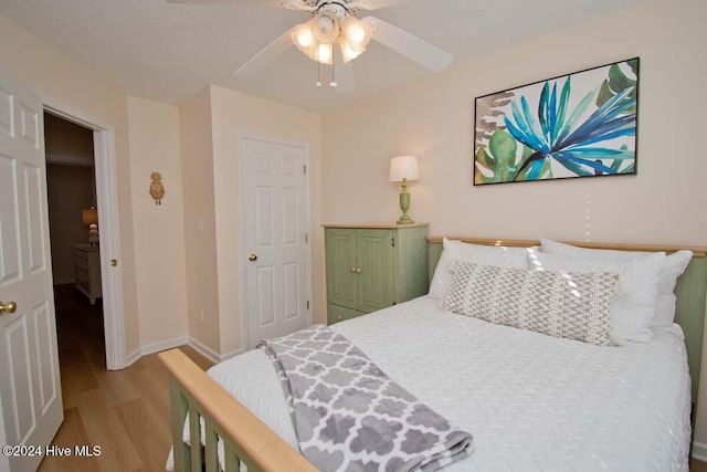 bedroom featuring a textured ceiling, light wood-type flooring, and ceiling fan