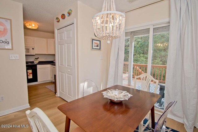 dining room featuring light hardwood / wood-style flooring, a notable chandelier, and a textured ceiling