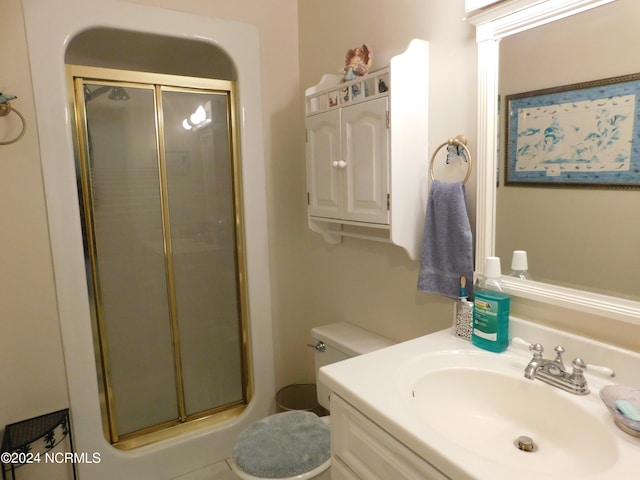 bathroom featuring a shower with door, toilet, and vanity