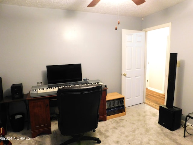 carpeted office space with a textured ceiling and ceiling fan