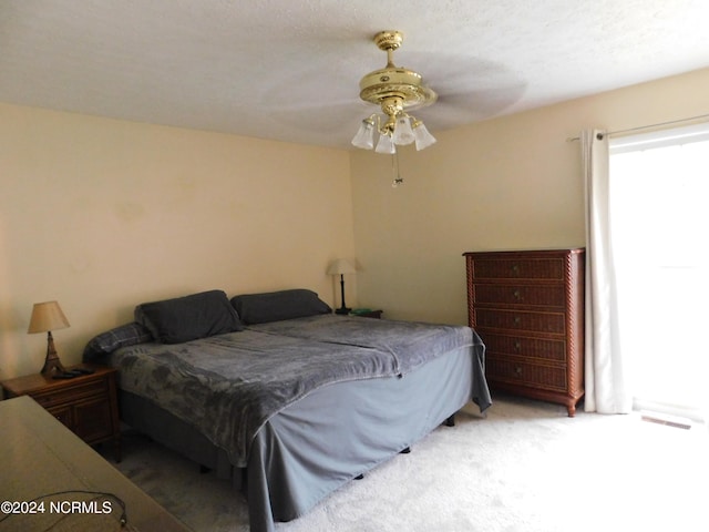 carpeted bedroom with ceiling fan and a textured ceiling