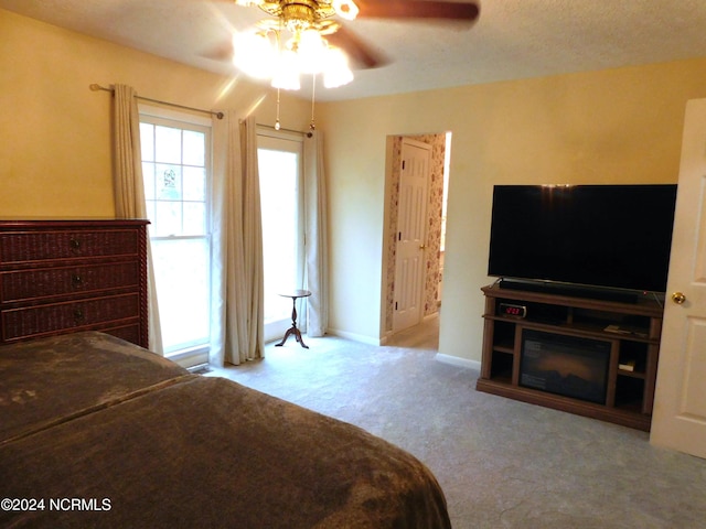 carpeted bedroom featuring ceiling fan and a textured ceiling