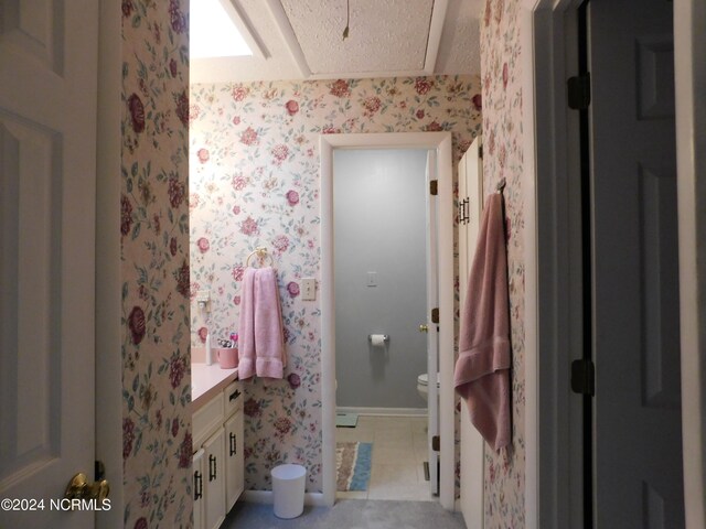 bathroom featuring a textured ceiling, vanity, toilet, and tile patterned floors