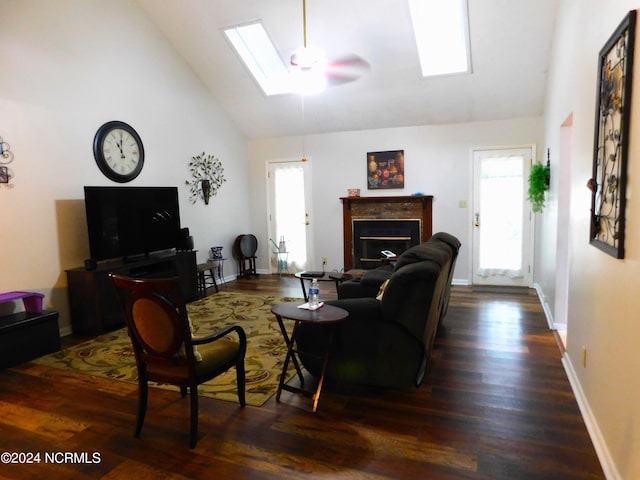 living room with dark hardwood / wood-style flooring, ceiling fan, a skylight, and high vaulted ceiling