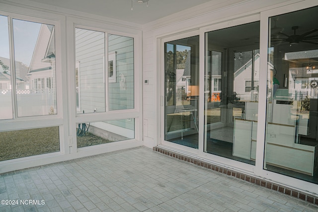 unfurnished sunroom with ceiling fan