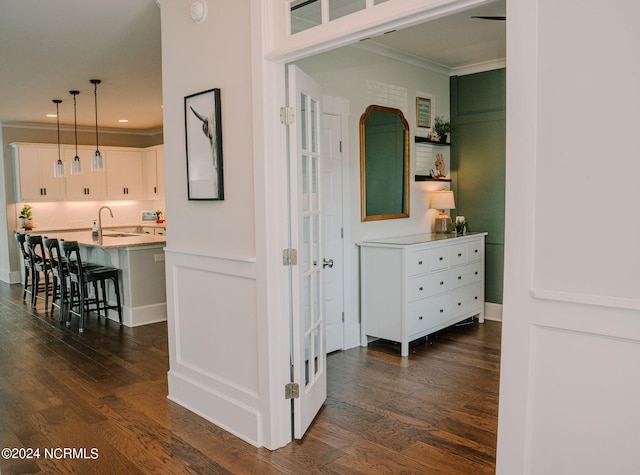 hall with crown molding, dark wood-type flooring, and sink