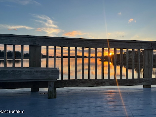 deck at dusk featuring a water view