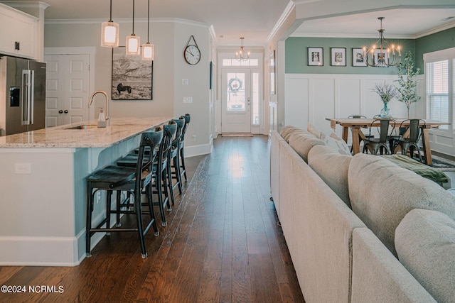 kitchen with sink, white cabinets, hanging light fixtures, high end fridge, and an inviting chandelier