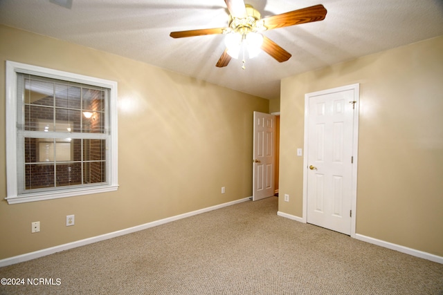 carpeted empty room with ceiling fan and a textured ceiling