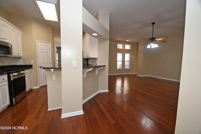 kitchen featuring ceiling fan, appliances with stainless steel finishes, dark wood-type flooring, and white cabinetry